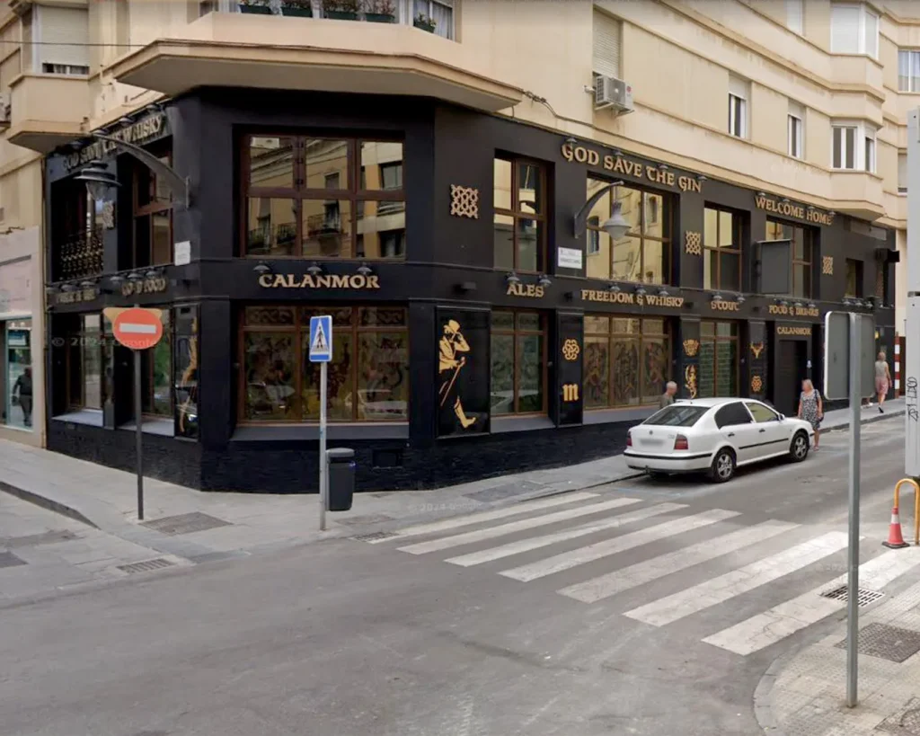 Fachada del Pub Calan Mor en Málaga con rótulos tradicionales pintados a mano sobre vidrio y pan de oro