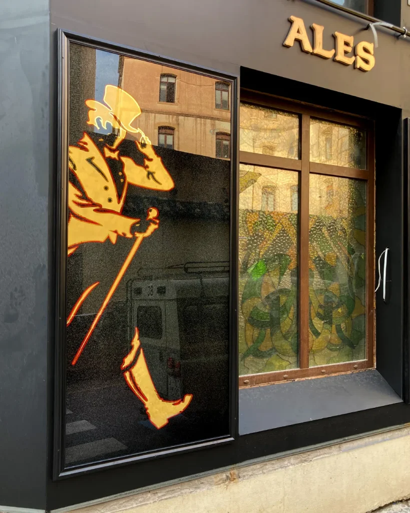 Rótulo publicitario de Johnnie Walker pintado a mano sobre vidrio con pan de oro en fachada de pub en Málaga