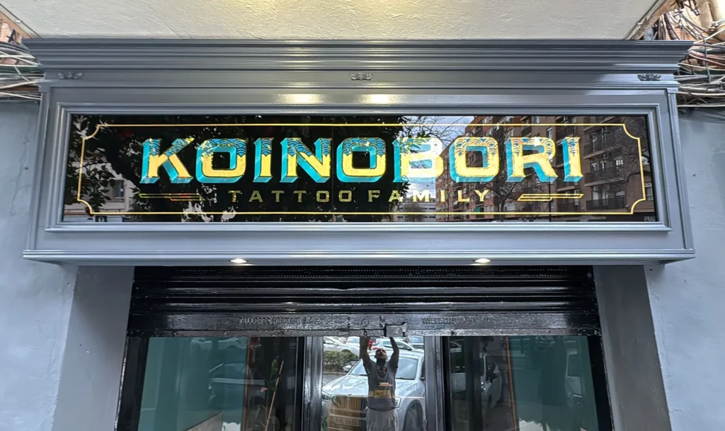 Rótulo tradicional de madera con vidrio rotulado a mano y pan de oro para estudio de tatuajes en Valencia